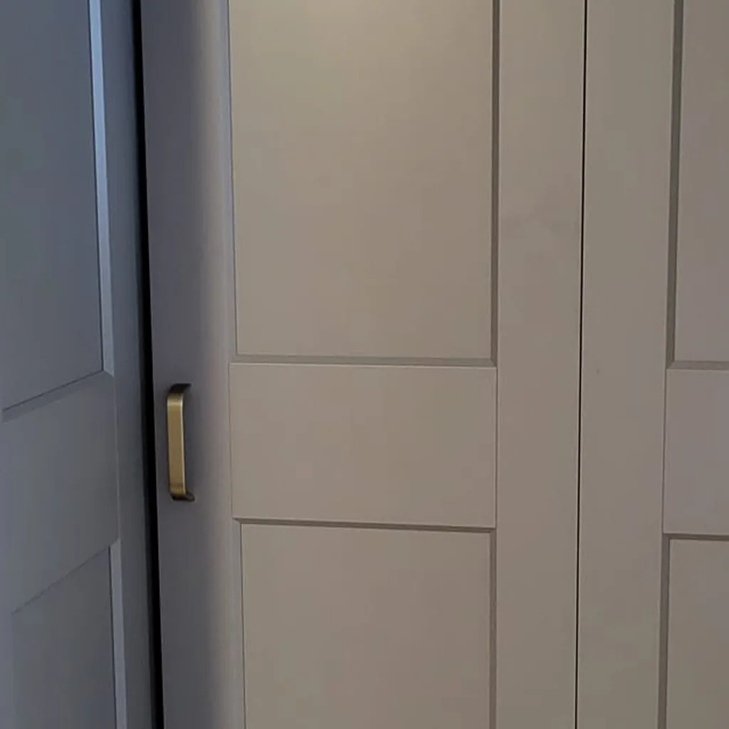 Detail van grijze IKEA PAX kast met scharnierdeur en messingkleurige handgreep