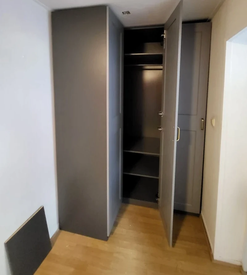 Grijze IKEA PAX hoekkast met geopende scharnierdeur, volledig in beeld