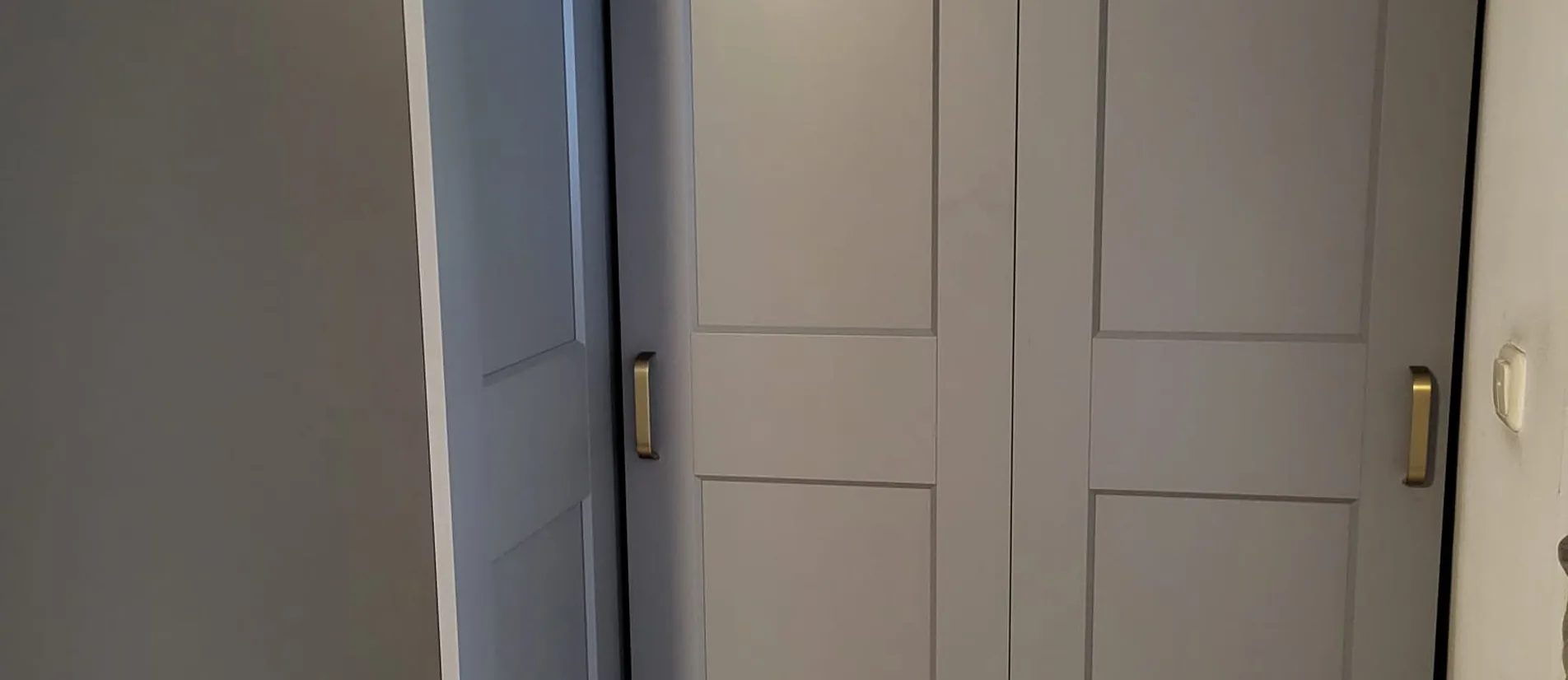Grijze IKEA PAX hoekkast met scharnierdeuren professioneel gemonteerd in een smalle hal
